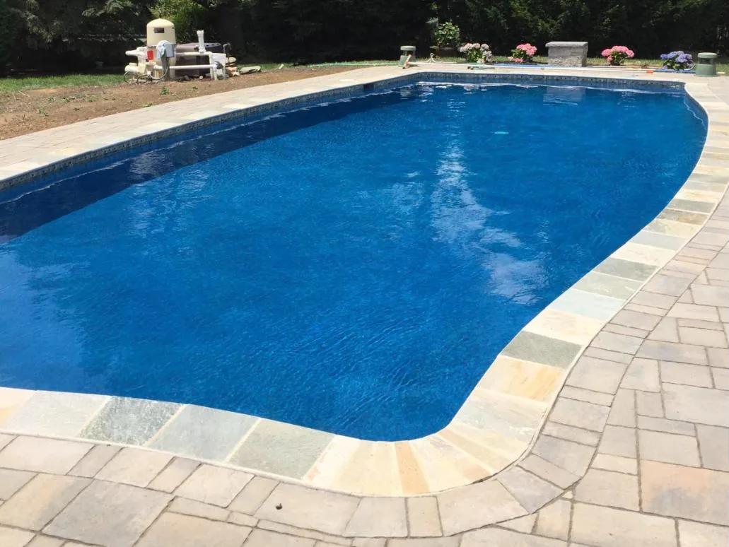Freeform pool with bluestone coping and a paver deck