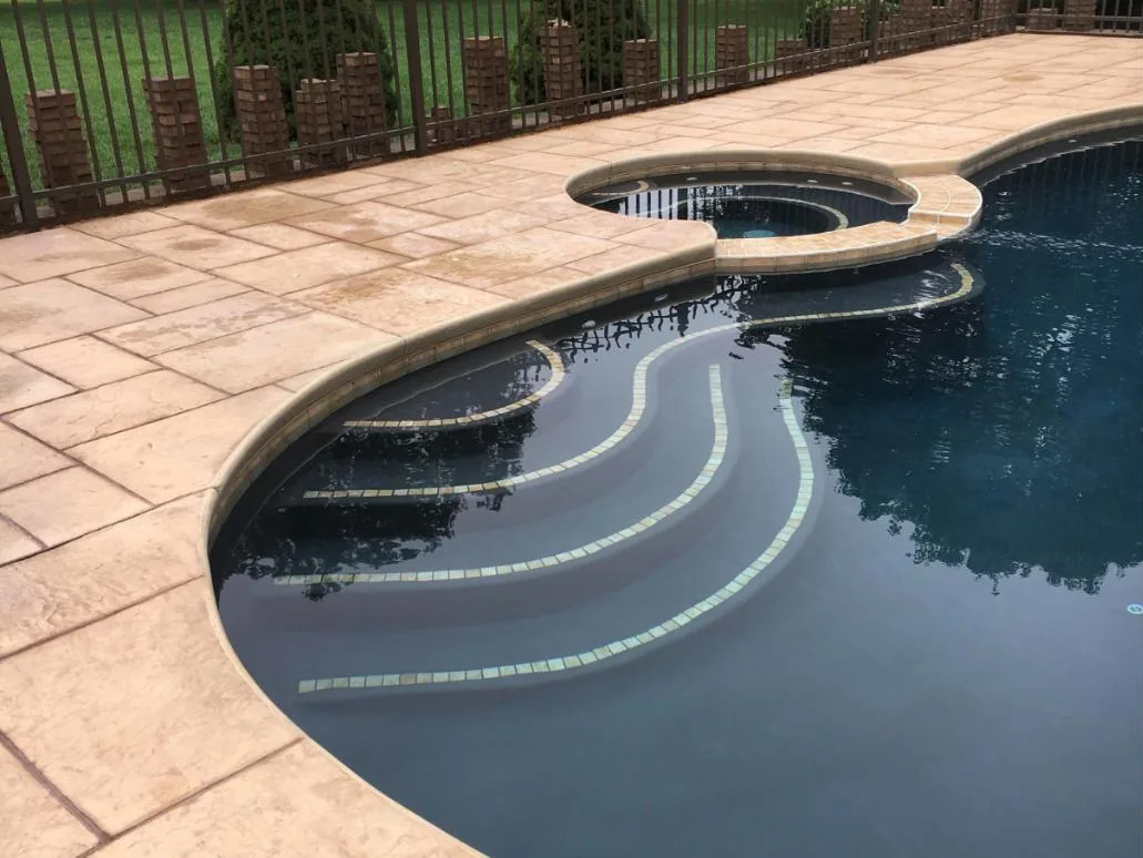 Curved entry steps with tile trim leading to a raised spa and stamped concrete deck