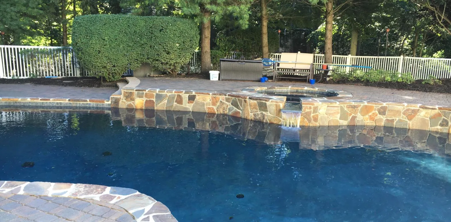 Flagstone raised spa with a spillover into a dark-finish pool