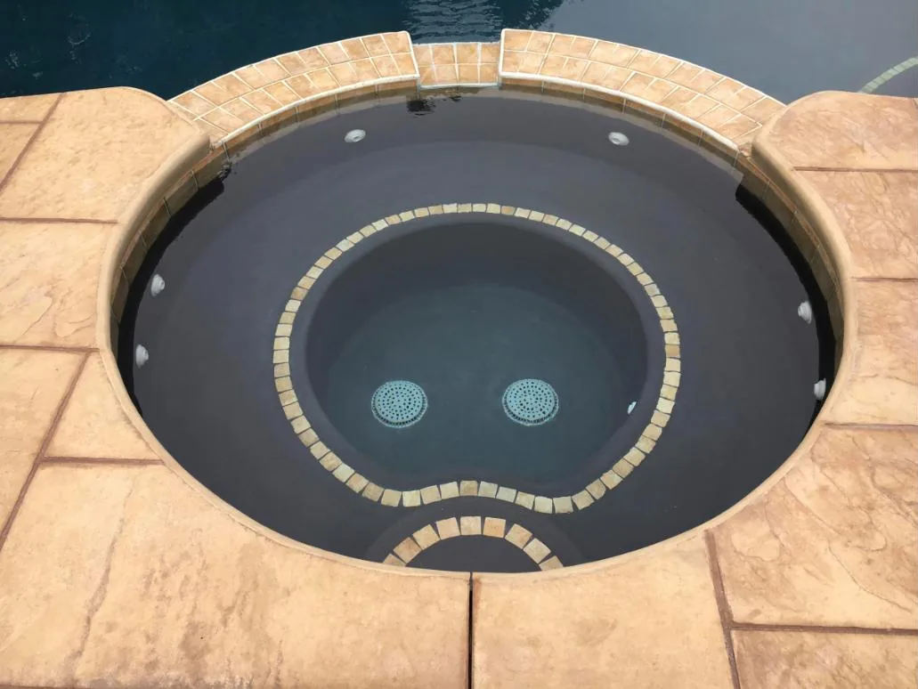 Round spa with a ring of tan accent tile set into the bench